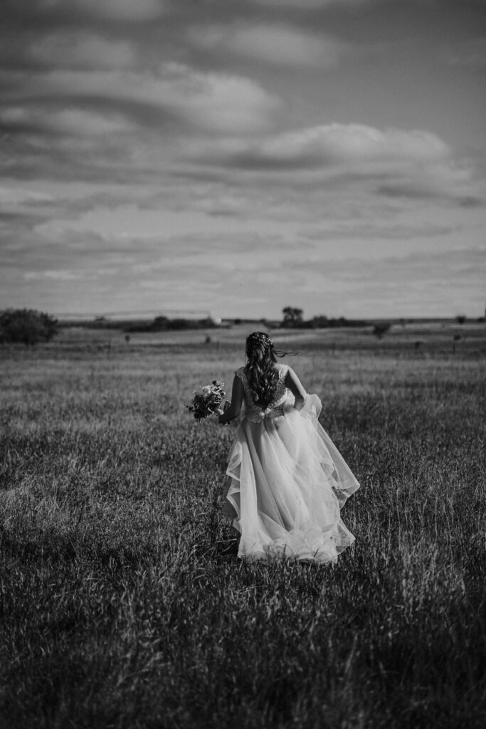 stunning bride in the country walking through field cinematic feel central alberta photographer